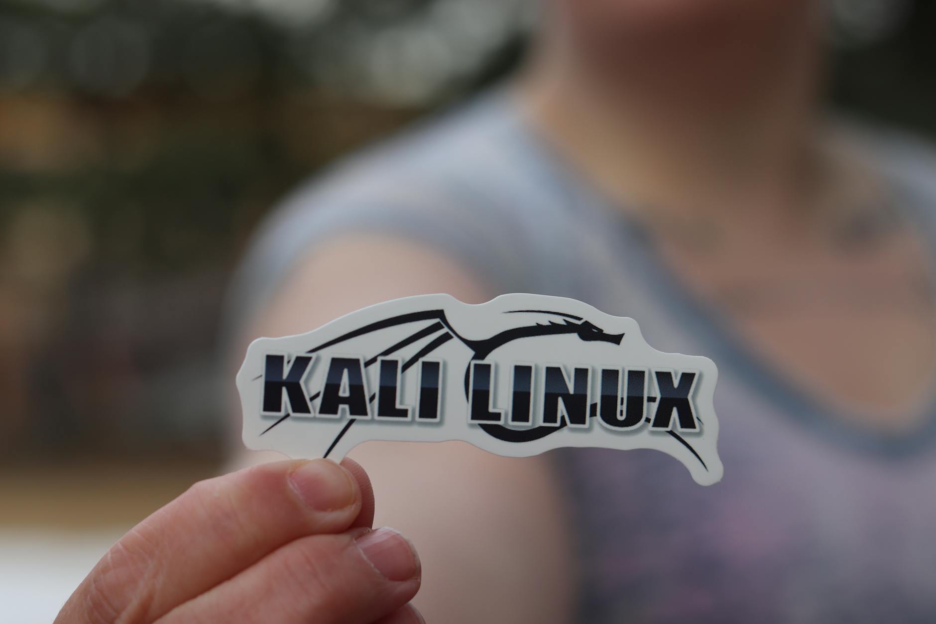 Dłoń trzymająca naklejkę Kali Linux podkreślającą temat cyberbezpieczeństwa