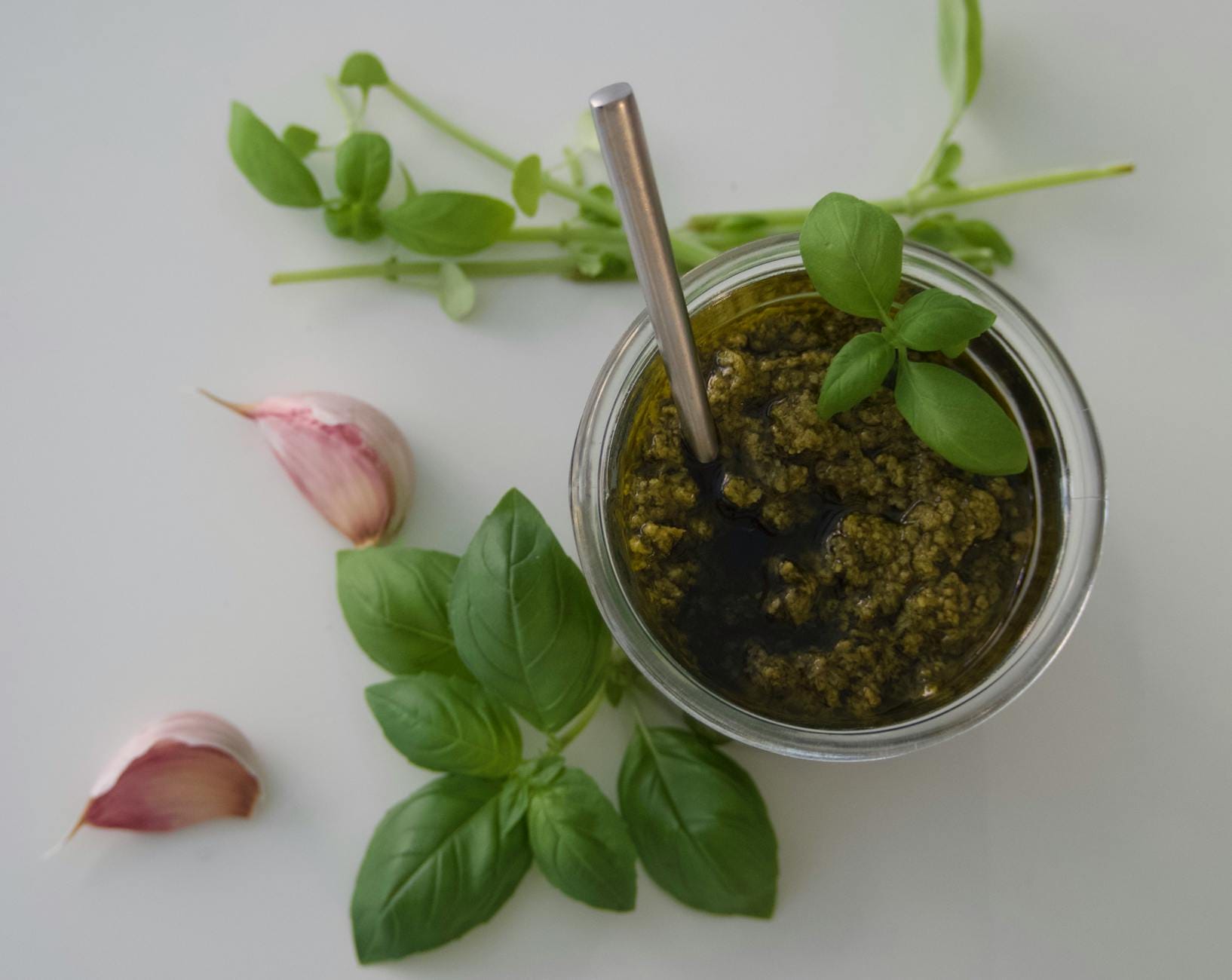 Miska z domowym pesto bazyliowym z ząbkami czosnku i liśćmi bazylii